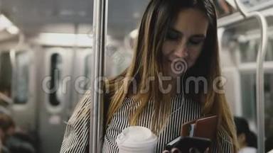 快乐成功的博客女孩在地铁列<strong>车上</strong>享受<strong>音乐</strong>智能手机应用程序耳机微笑咖啡杯。